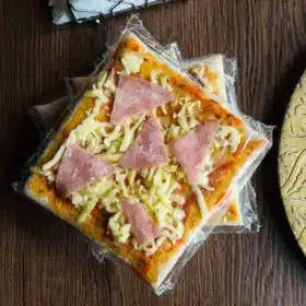 Pizza personalizada 15 x 15 cm Pizza personalizada de 15 x 15 cm, precocida y congelada, con ingredientes como jamón, aceitunas, 4 quesos o vegetariana, lista para hornear y disfrutar.